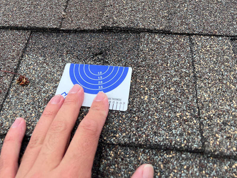Roofer measuring hail damage before repair